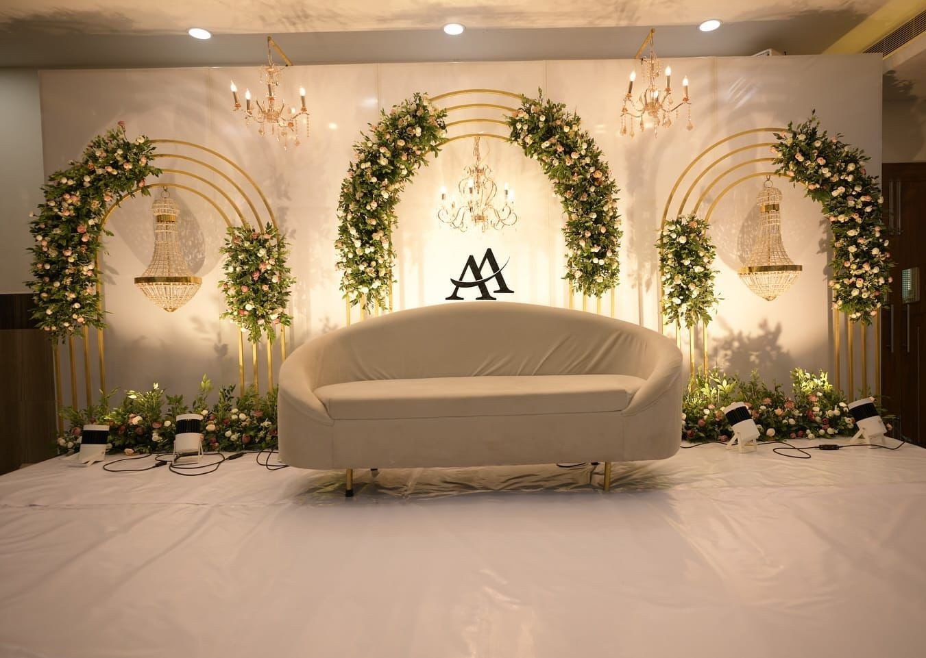 Engagement stage with white arches and greenery